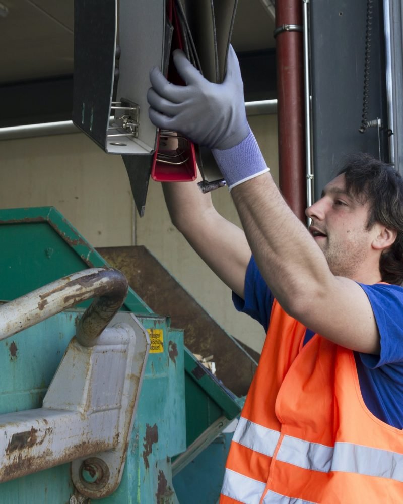 worker-at-a-waste-container-throwing-away-folders.jpg